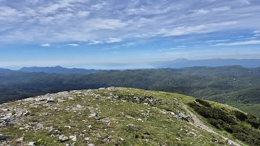 Razgled s poti na Snežnik, gorski teren in modro nebo.